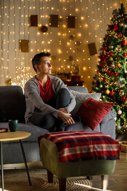 istock Thoughtful woman sitting on sofa at Christmas looking away 2185993705