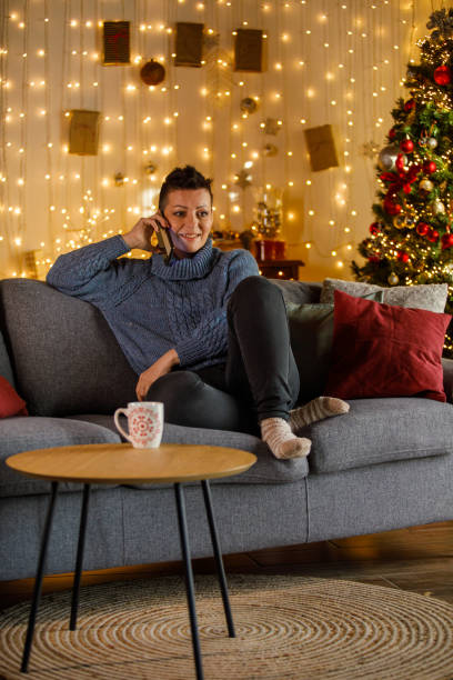 istock Woman sitting on sofa at home, talking on her mobile phone 2185993718