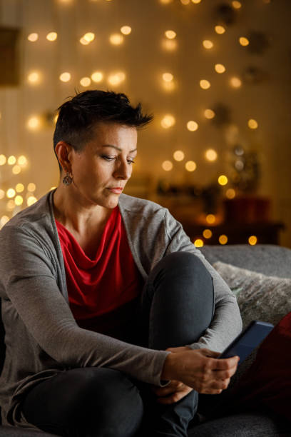 istock Thoughtful woman sitting on sofa at Christmas looking away 2185993723