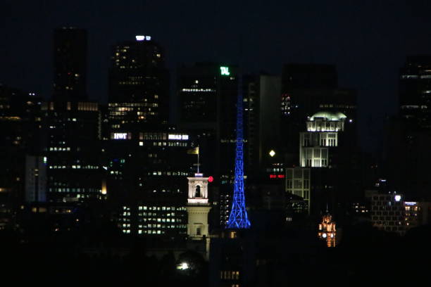 Government house is light up with the art centre spire in blue behind in Melbourne and to the right flinders street station.