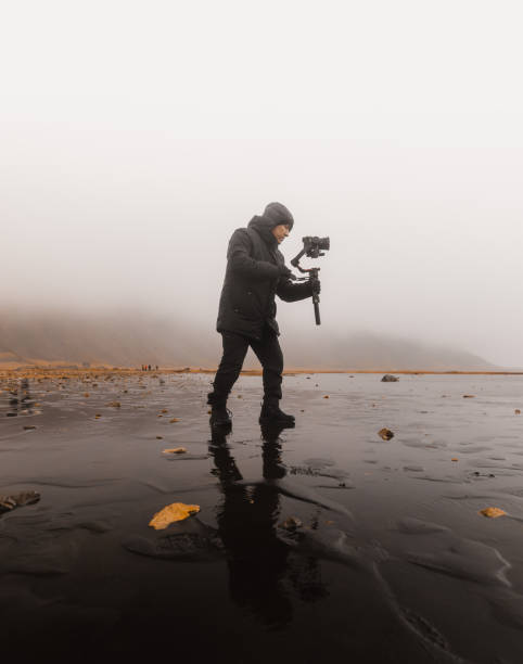 Videographer capturing footage on a foggy beach with gimbal stabilizer