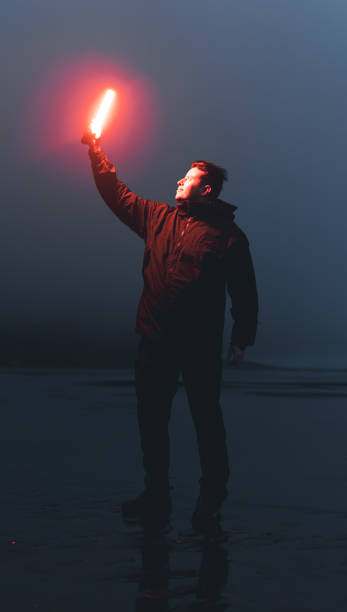 Man holding flare standing on beach at night