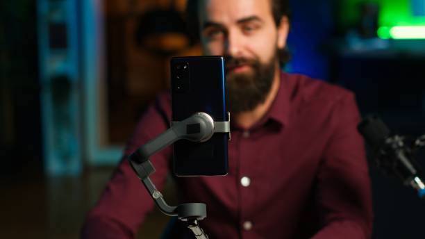 istock Focus on cellphone on selfie stick used by influencer in studio recording live 2186021551