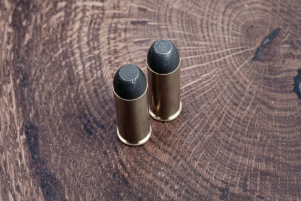 Old West era Long Colt .45 caliber revolver cartridges Old West era Long Colt .45 caliber revolver cartridges on a wooden table forty five caliber handgun stock pictures, royalty-free photos & images