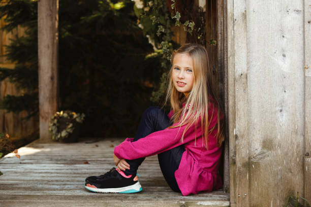 a cute little girl is sitting on a bench and raised her hands as if to take something