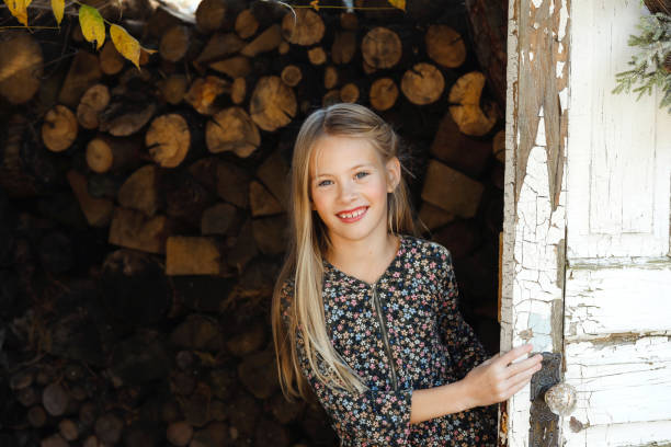 A beautiful, eight-year-old girl smiles at the camera as she peeks out from behind a door. Shot with a Canon 5D Mark IV.