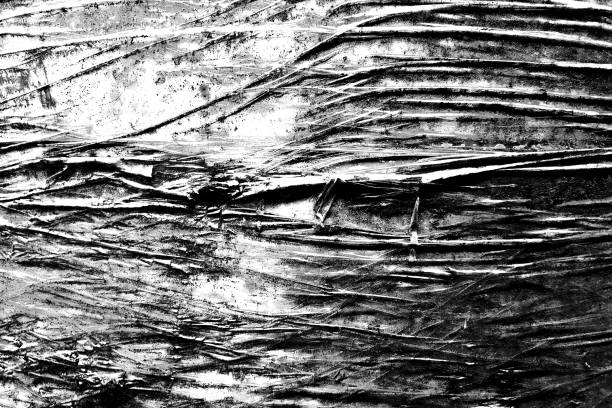 Black and white abstract texture of crumpled plastic material with sharp contrasts and detailed patterns, ideal for backgrounds or design elements.