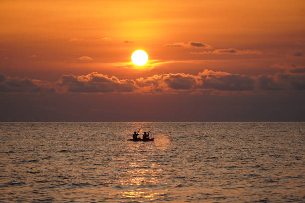 Sunset with seascape in foreground with large colourful sunAsia