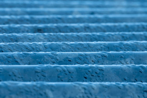 Condensed dewdrops on rusted corrugated galvanized iron roofing sheet of old building in the early morning at Northern Thailand, natural light