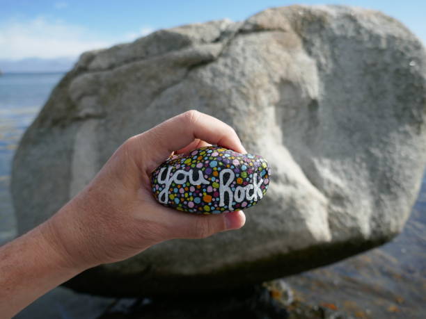 istock You rock kindness rock held in hand in front of large boulder rock 2186049385