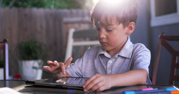 istock Little boy using his digital tablet sitting at his home backyard 2186050418