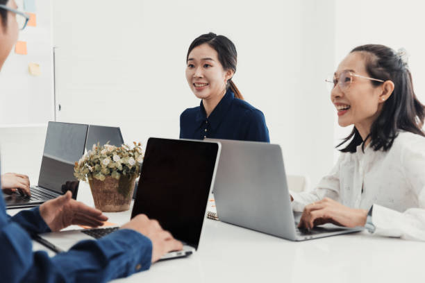 istock Team collaborating in a modern office setting, engaged in a productive meeting with laptops at a bright table 2186064288