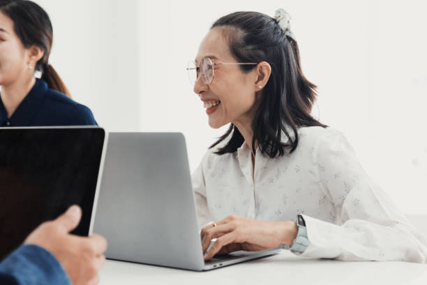 istock Smiling woman working on laptop during collaborative meeting in modern office space with colleagues 2186064378
