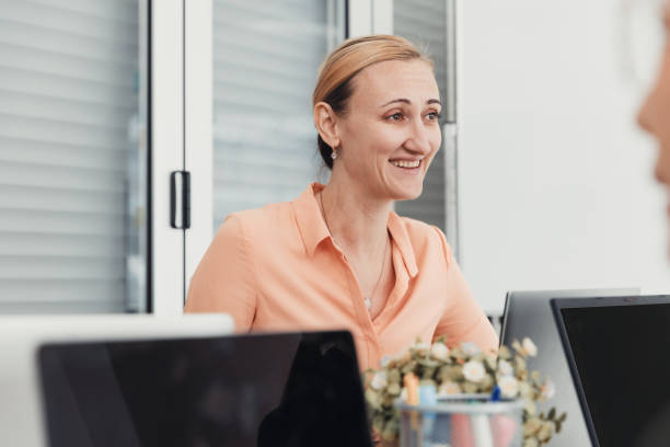istock Smiling woman engaged in conversation during a modern office meeting in a bright space 2186064414