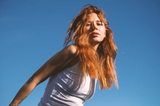 Close up portrait of a beautiful young redhead woman. Attractive teenage girl looking to camera against a bright green background.