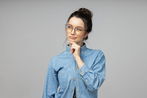 istock A young woman in glasses thinks on a gray background 2186093582