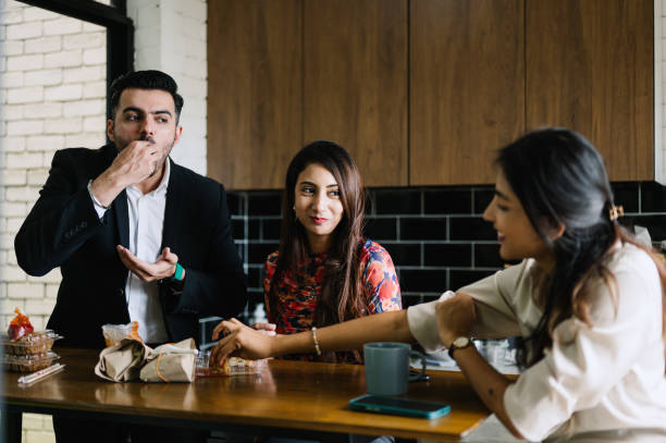 istock Asian Indian office worker enjoying lunch at work together in company kitchen. 2186094120