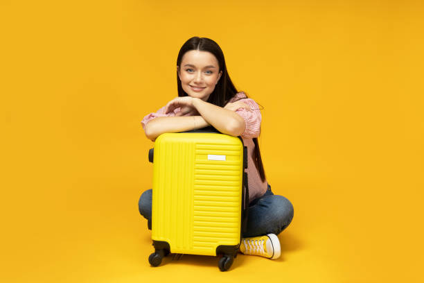 istock Happy young girl with a suitcase on a yellow background 2186095536