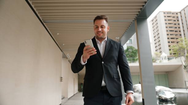istock Happy project manager checking mobile phone while walking at corridor. Urbane. 2186095818