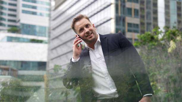 istock Businessman standing at rooftop while talking with team by using phone. Urbane 2186097394
