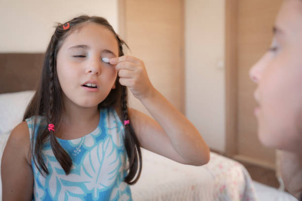Cute little girl applying make-up and looking at her reflection in mirror