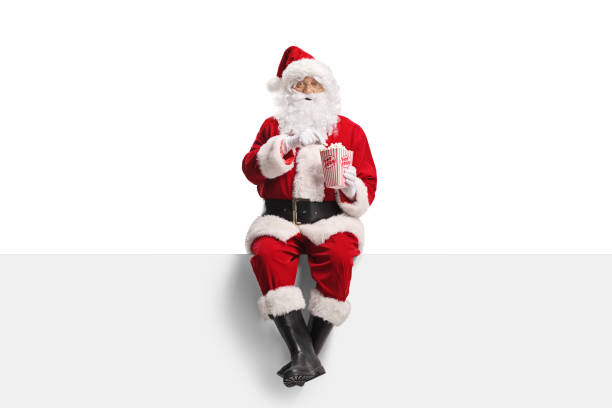 istock Santa Claus sitting on a blank panel and holding a box of popcorn 2186107339