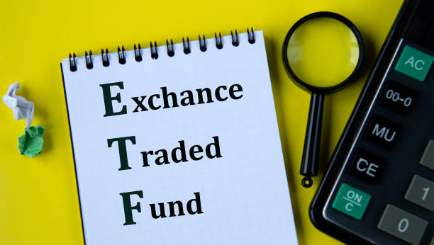 istock ETF - abbreviation in a white notebook with a calculator and a magnifying glass on a yellow plan 2186107635