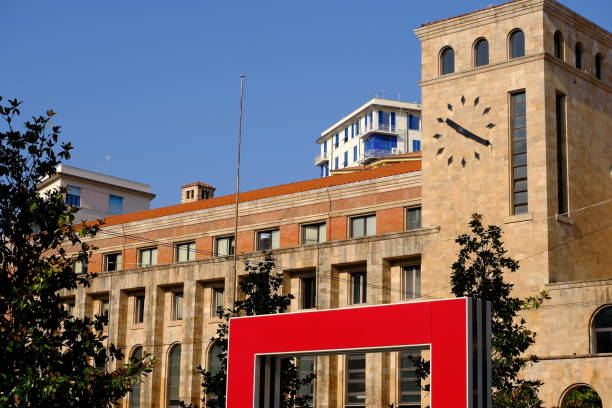 La Spezia, Italy about 09/2021. Tower with clock and red doors in the square. Palazzo delle poste in La Spezia designed by Angiolo Mazzoni and elements of art by Daniel Buren. Stone and brick.