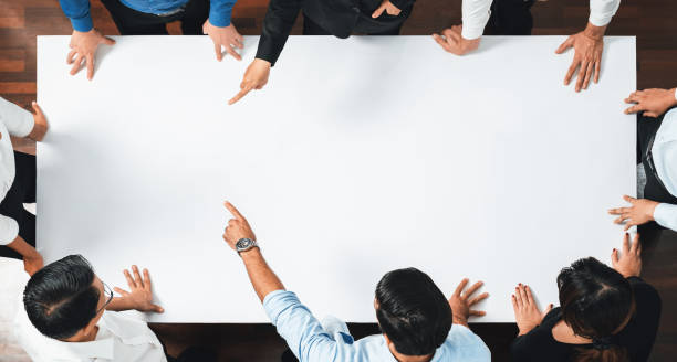 istock Businesspeople on meeting table pointing to empty space. Prudent 2186118555