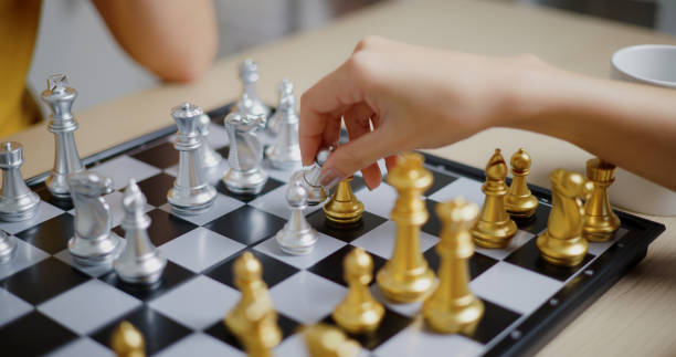 istock Close-up of a young woman's hand moves a considered chess piece forward. 2186126820