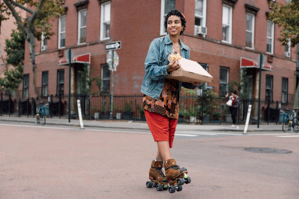 Young woman on roller skates enjoying a pizza slice while riding in Williamsburg, Brooklyn New York.
