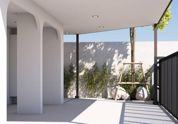 istock A modern carport with sleek white columns and a tiled floor, bordered by green bamboo plants and a small tree with a wooden support frame. Natural light creates soft shadows. 3d rendering 2186137516