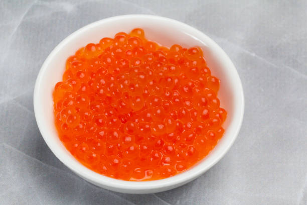 istock Red salmon caviar in a white bowl on the kitchen table. 2186156976