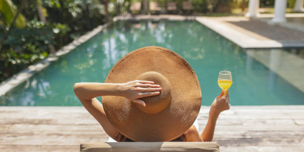 Woman Relaxing with Drink by Tropical Pool
