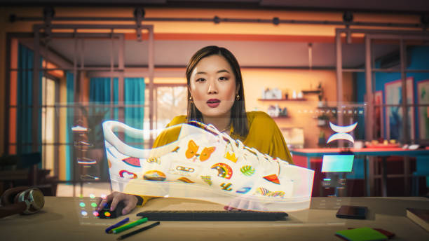 istock Asian Female Designer Uses a VFX Hologram Screen to Create a 3D Shoe Design in Graphical Interface Software. Young Professional Entrepreneur doing Digital Fashion, Sneaker and Clothing Design 2186170827