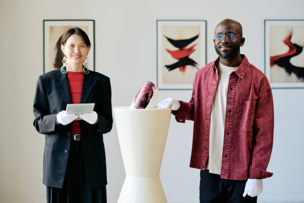 istock Smiling Art Curators Showing Modern Abstract Sculpture 2186179516