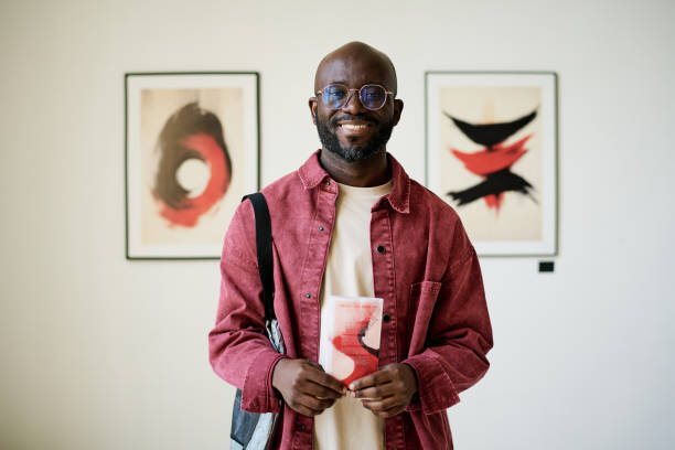 Smiling Man Holding Red Book in Art Gallery