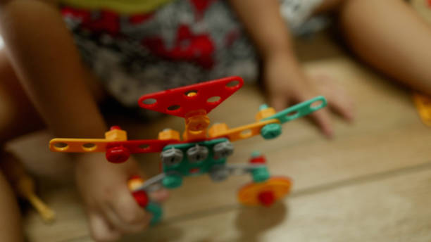 Asian boy plays with nuts and builds robots, learning how to use tools toy at home.