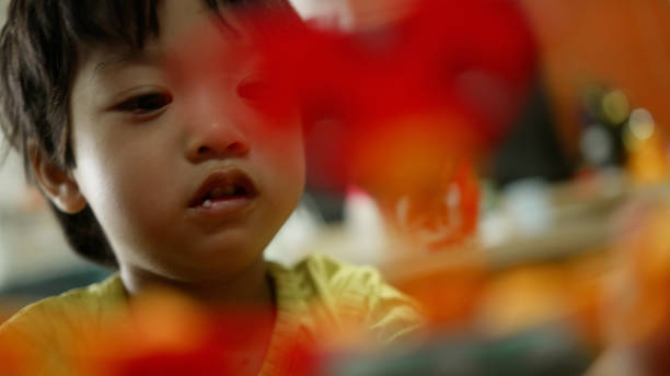 Asian boy plays with nuts and builds robots, learning how to use tools toy at home.