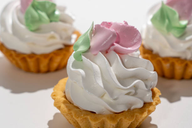 istock Three small cupcakes with white frosting and green and pink decorations 2186200039