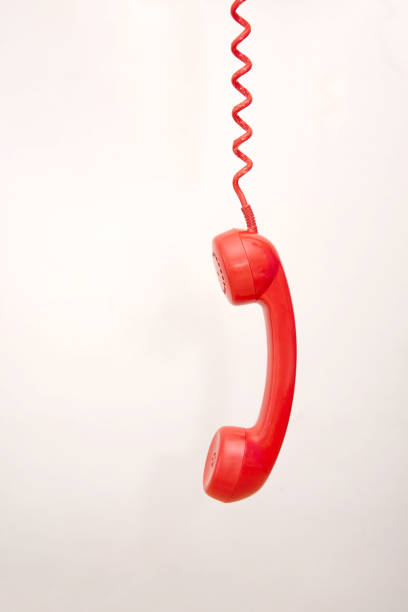 istock Red telephone receiver hanging by coiled cord on light grey background 2186214144