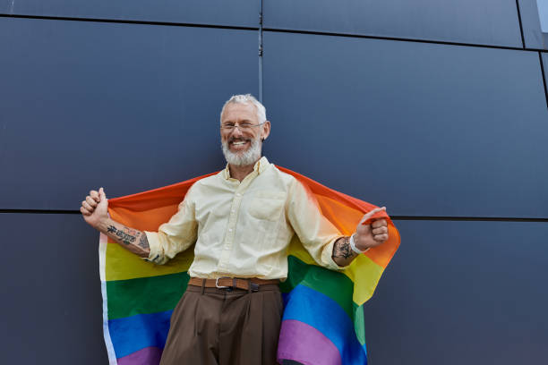 istock Handsome mature man joyfully celebrates pride with a rainbow flag amidst modern architecture 2186214915