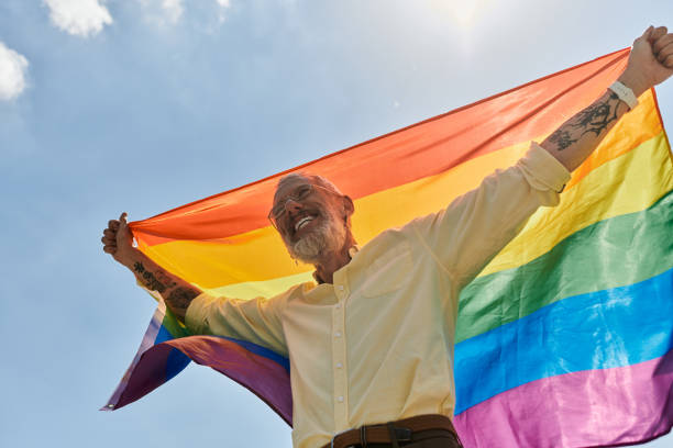 istock Joyful celebration of pride and identity under a bright sky by a mature man with a rainbow flag 2186215012