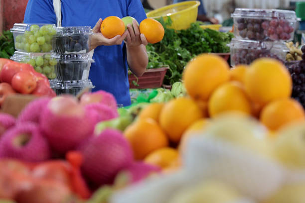 Focus on Asian woman buying fresh fruits at Asian morning market