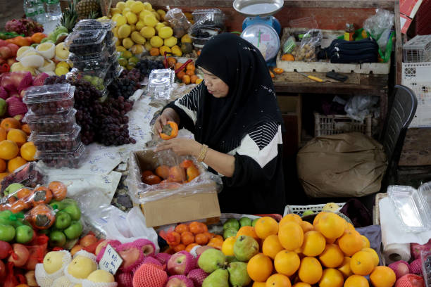 Focus on Muslim woman selling fresh fruits at Asian morning market