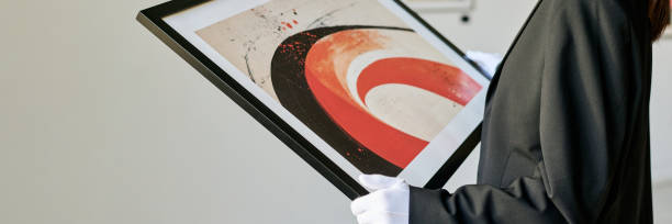 Individual holding modern abstract painting with bold curved lines and vivid colors. The art piece captivates with its dynamic composition and expressive brushstrokes