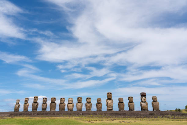 Afternoon sun shines down on the line of fifteen iconic Moai statues of Ahu Tongariki, on the eastern side of Easter Island. The Moai were constructed around five or six hundred years ago and represent the islanders' ancestors. They were all toppled after a period of tribal warfare broke out, though a number were restored in the twentieth century.