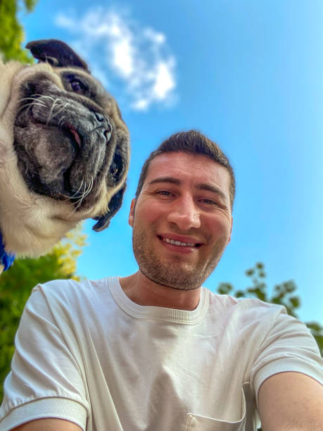 istock Happy man and pug dog looking camera, taking selfie portrait - bottom view, vertical shot 2186246513