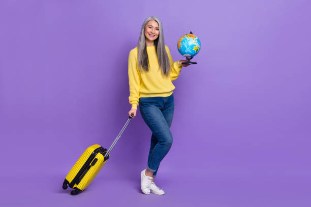 Photo of funky charming lady pensioner dressed pullover carrying baggage holding globe isolated purple color background