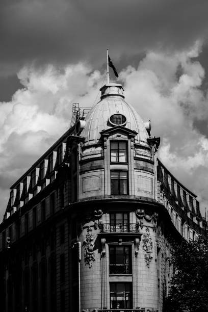 istock Clock tower stands tall as pedestrians stroll amidst cloudy skies in grayscale 2186268572